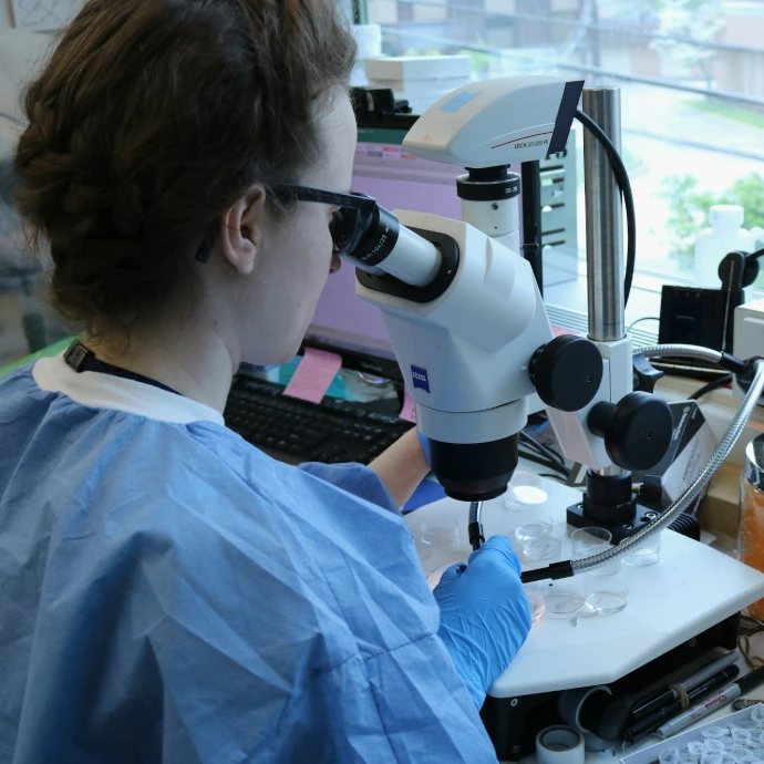 a woman in a lab coat looking through a microscope